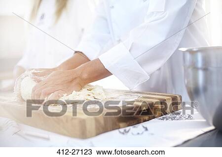 Stock Image - Chef kneading dough on cutting board baking in kitchen. Fotosearch