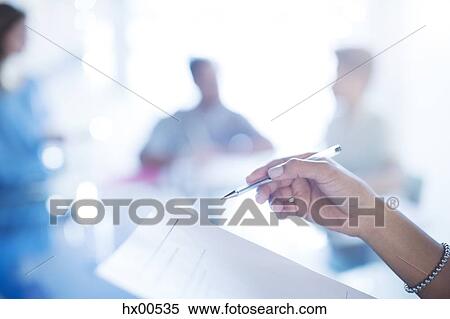 Stock Photography - Close up businesswoman holding pen reviewing paperwork. Fotosearch