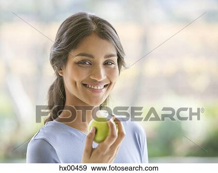 Stock Photo - Close up portrait smiling woman eating green apple. Fotosearch