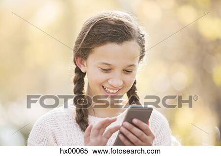 Close up smiling girl texting with cell phone outdoors View Large Photo Image Stock Photography - Close up smiling girl texting with cell phone outdoors. Fotosearch