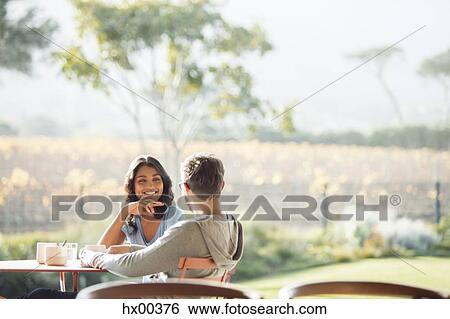 Couple drinking coffee and talking on sunny patio View Large Photo Image Stock Photograph - Couple drinking coffee and talking on sunny patio. Fotosearch