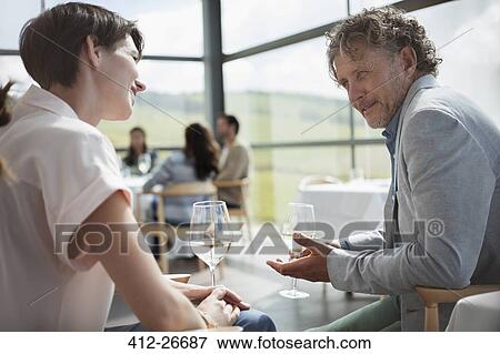 Couple drinking wine and talking in restaurant View Large Photo Image Stock Photo - Couple drinking wine and talking in restaurant. Fotosearch