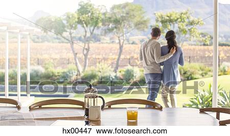 Stock Photo - Couple hugging on patio overlooking field. Fotosearch