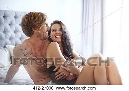 Stock Image - Couple laughing and hugging on bed. Fotosearch