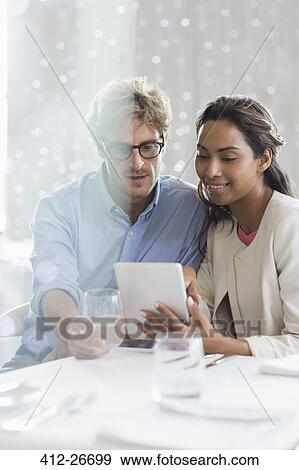 Couple using digital tablet at restaurant table View Large Photo Image Stock Photo - Couple using digital tablet at restaurant table. Fotosearch
