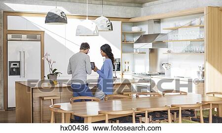 Stock Photograph - Couple using digital tablet in kitchen. Fotosearch