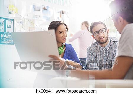 Stock Image - Creative business people discussing paperwork in office. Fotosearch