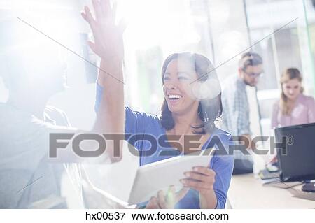Stock Photo - Creative business people high fiving with digital tablet. Fotosearch