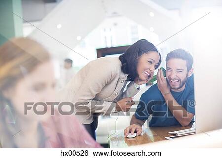 Stock Photograph - Creative business people sharing and listening to headphones in office. Fotosearch