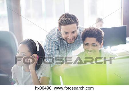 Stock Image - Creative business people with headphones and coffee using computer in office. Fotosearch