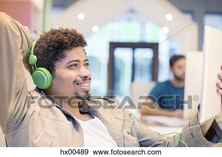 Creative businessman listening to headphones and using digital tablet View Large Photo Image Stock Photo - Creative businessman listening to headphones and using digital tablet. Fotosearch