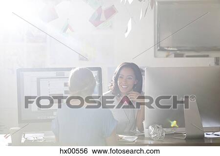 Creative businesswoman with headphones talking at computers in sunny office View Large Photo Image Stock Photograph - Creative businesswoman with headphones talking at computers in sunny office. Fotosearch
