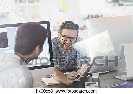 Creative designers talking between computers in office View Large Photo Image Stock Image - Creative designers talking between computers in office. Fotosearch