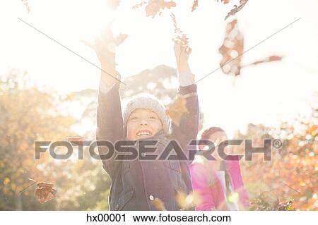 Stock Image - Enthusiastic boy playing in autumn leaves. Fotosearch