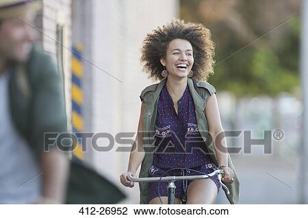 Enthusiastic woman with afro riding bicycle View Large Photo Image Stock Image - Enthusiastic woman with afro riding bicycle. Fotosearch