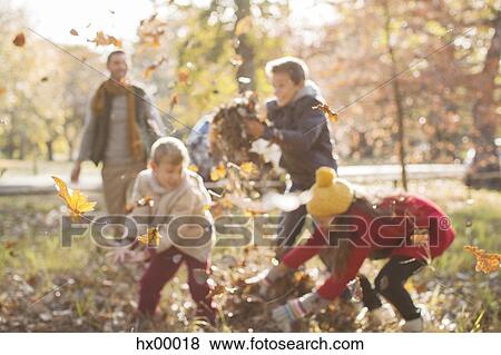 Family playing in autumn leaves at park View Large Photo Image Stock Photo - Family playing in autumn leaves at park. Fotosearch