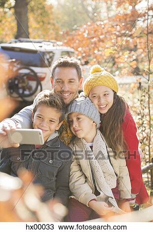 Stock Image - Family taking selfie among autumn leaves. Fotosearch