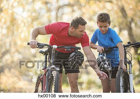 Father and son examining wheel on mountain bike View Large Photo Image Stock Photo - Father and son examining wheel on mountain bike. Fotosearch