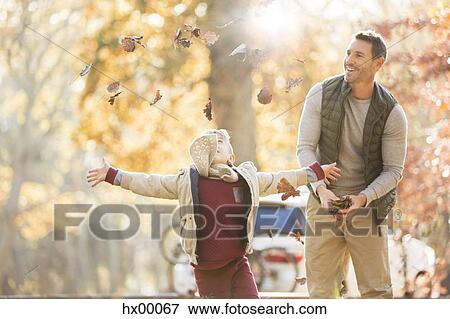 Father and son throwing autumn leaves overhead View Large Photo Image Stock Photo - Father and son throwing autumn leaves overhead. Fotosearch