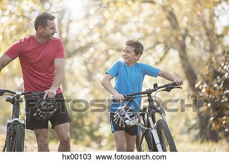 Father and son walking mountain bikes in woods View Large Photo Image Stock Image - Father and son walking mountain bikes in woods. Fotosearch