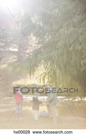 Stock Photo - Father and sons preparing fishing rods in woods. Fotosearch