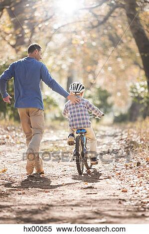 Father teaching son to ride bicycle on path in woods View Large Photo Image Stock Photography - Father teaching son to ride bicycle on path in woods. Fotosearch