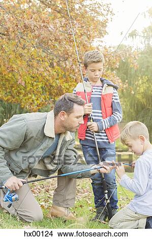 Picture - Father teaching sons to prepare fishing rods. Fotosearch