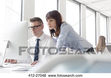 Focused businessman and businesswoman working at computer in office View Large Photo Image Stock Photo - Focused businessman and businesswoman working at computer in office. Fotosearch