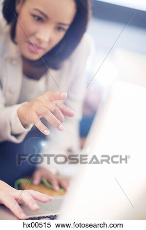Stock Photography - Focused businesswoman pointing at laptop. Fotosearch
