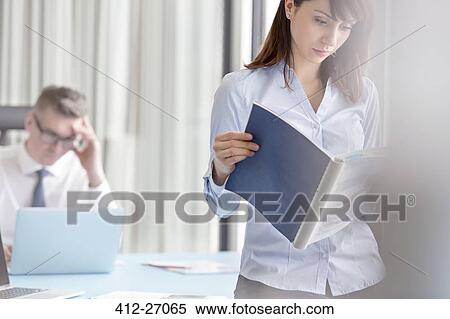 Focused businesswoman reading report in office View Large Photo Image Stock Photography - Focused businesswoman reading report in office. Fotosearch