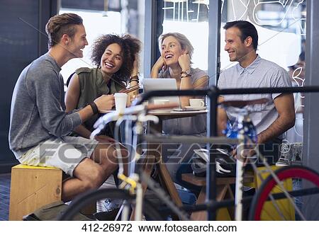 Stock Image - Friends hanging out in cafe behind bicycle. Fotosearch