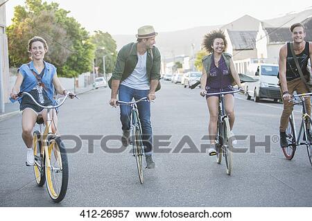 Friends riding bicycles in a row on street View Large Photo Image Stock Photo - Friends riding bicycles in a row on street. Fotosearch