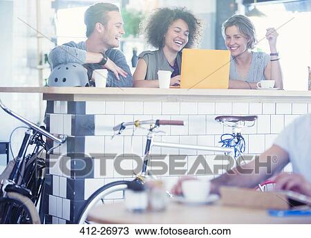 Stock Image - Friends sharing laptop at cafe bar. Fotosearch