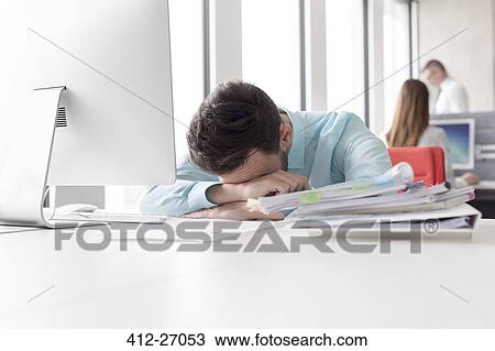 Frustrated businessman with head down next to stack of reports on desk View Large Photo Image Stock Image - Frustrated businessman with head down next to stack of reports on desk. Fotosearch