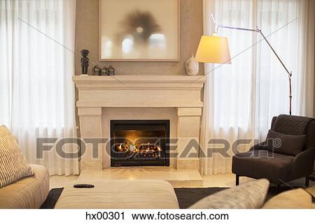 Stock Image - Illuminated floor lamp near marble fireplace. Fotosearch