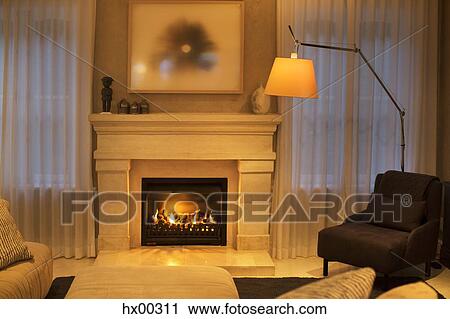 Stock Image - Illuminated floor lamp next to marble fireplace. Fotosearch