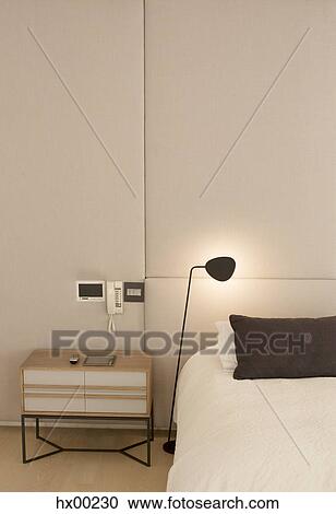 Stock Image - Illuminated lamp over bed. Fotosearch