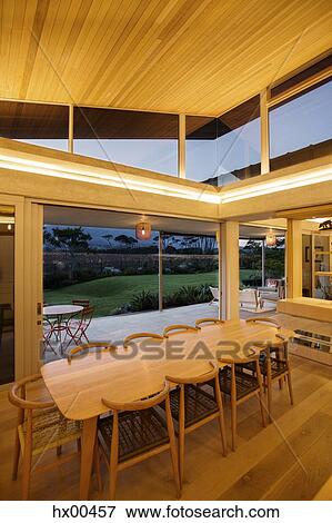 Illuminated slanted wood ceiling over long dining table View Large Photo Image Stock Photo - Illuminated slanted wood ceiling over long dining table. Fotosearch