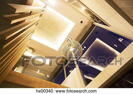 Stock Image - Illuminated tray ceiling and modern pendant light hanging in luxury foyer. Fotosearch