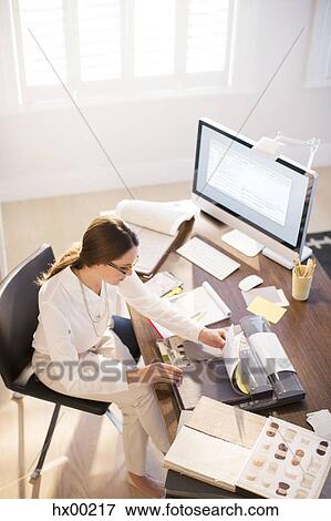 Stock Photo - Interior designer examining carpet swatches at desk. Fotosearch