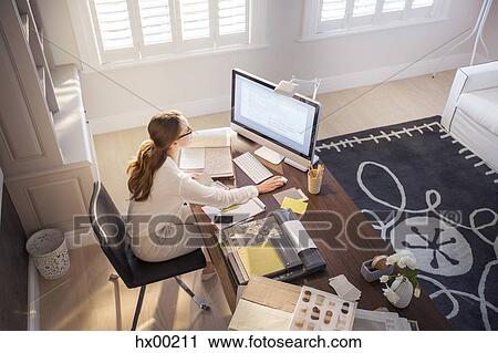 Stock Image - Interior designer working at computer in home office. Fotosearch