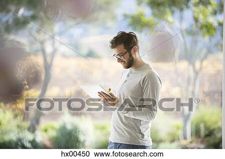 Man drinking orange juice and using digital tablet on patio View Large Photo Image Stock Image - Man drinking orange juice and using digital tablet on patio. Fotosearch