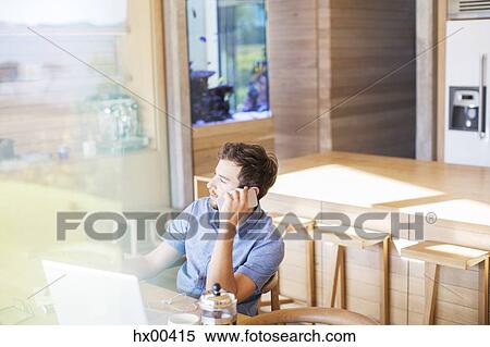 Man talking on cell phone at laptop in kitchen View Large Photo Image Stock Photography - Man talking on cell phone at laptop in kitchen. Fotosearch