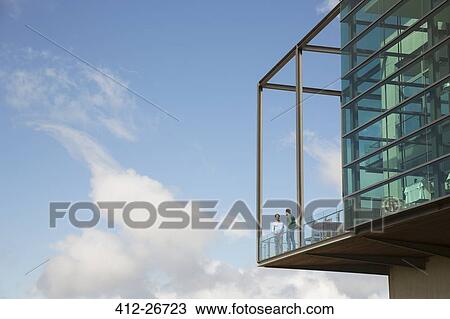 Men talking on balcony of glass bump out against blue sky View Large Photo Image Stock Image - Men talking on balcony of glass bump out against blue sky. Fotosearch