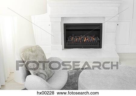 Stock Photo - Modern chair and floor lamp next to marble fireplace in living room. Fotosearch