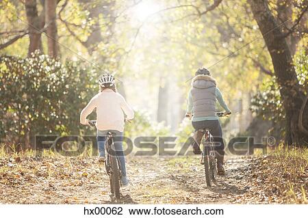 Mother and daughter bike riding on path in woods View Large Photo Image Stock Image - Mother and daughter bike riding on path in woods. Fotosearch