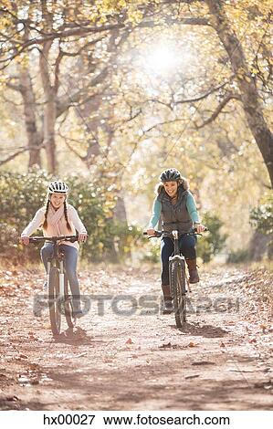 Mother and daughter bike riding on path in woods View Large Photo Image Stock Photo - Mother and daughter bike riding on path in woods. Fotosearch