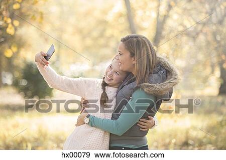 Stock Photo - Mother and daughter taking selfie outdoors. Fotosearch