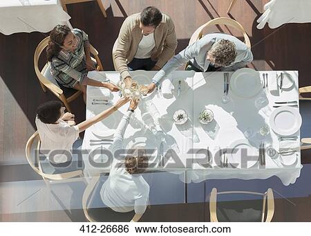 Overhead view friends toasting wine glasses at sunny restaurant table View Large Photo Image Stock Photograph - Overhead view friends toasting wine glasses at sunny restaurant table. Fotosearch