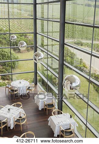Stock Image - Pendant lights hanging over tables in winery dining room. Fotosearch